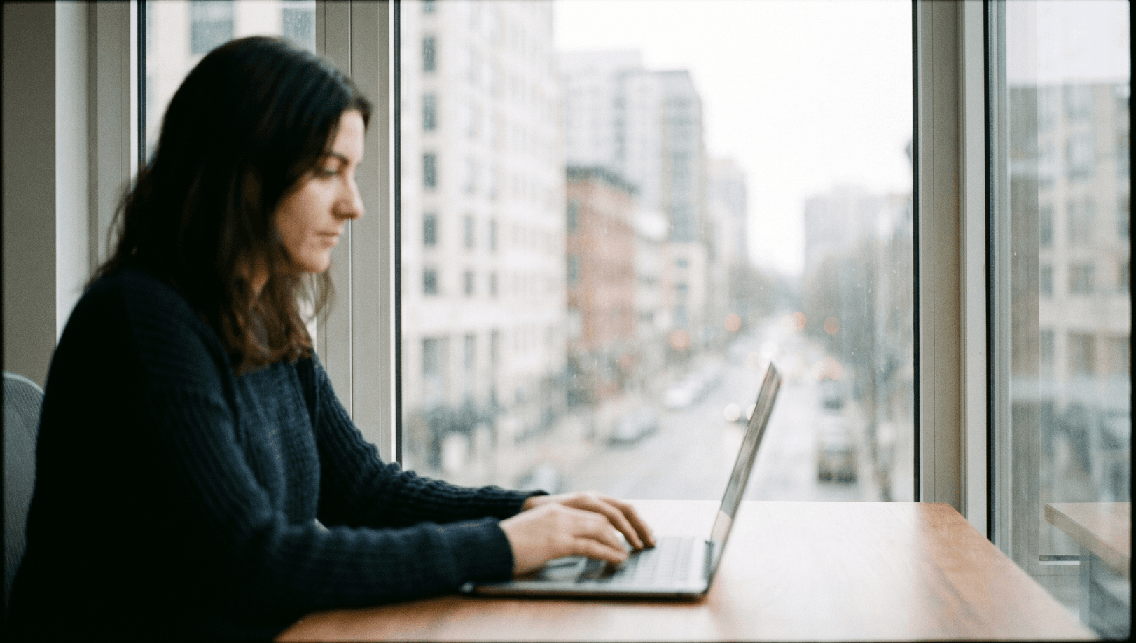 Silhouette of a person at a desk looking out a window